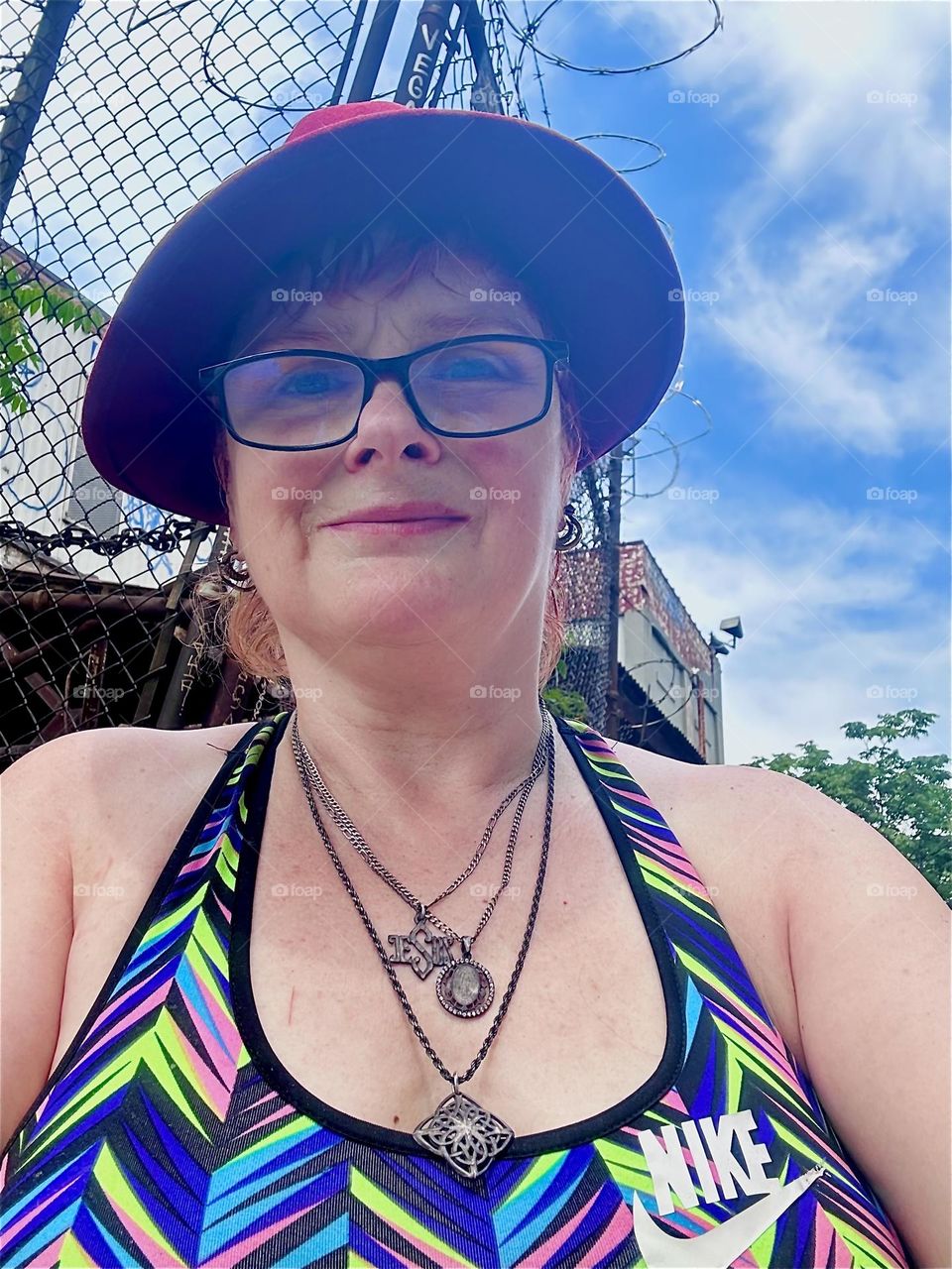 Wearing my favorite burgundy Fedora hat this is me, “Petra Schiller” a.k.a. “Maxine Firefox” a.k.a. „Maximiliane Feuerfuchs“ standing by the “East River” in the parking lot beneath the “Pulaski Bridge” in LIC, Queens. 2024. Hypnotic Productions