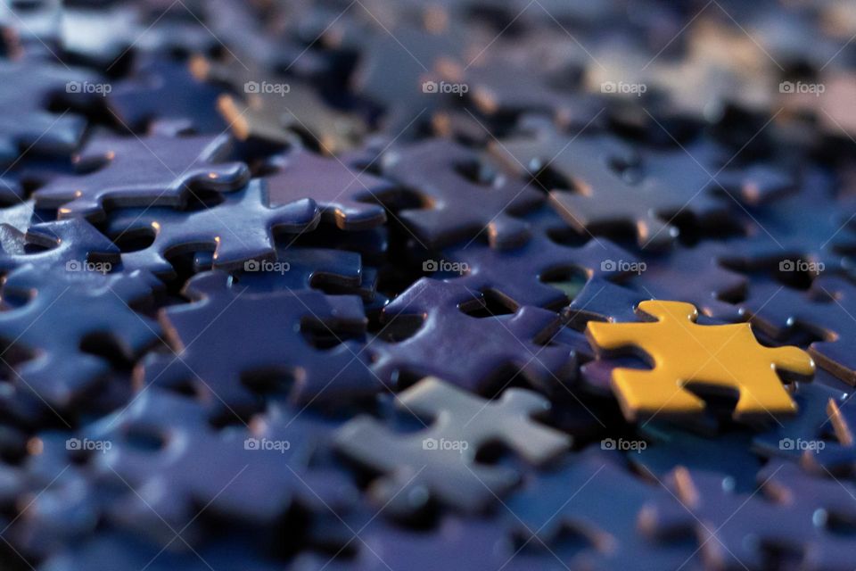 Many blue puzzle pieces and one yellow one