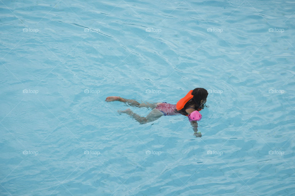 Girl swimming in the pool and enjoying of hot summer day 