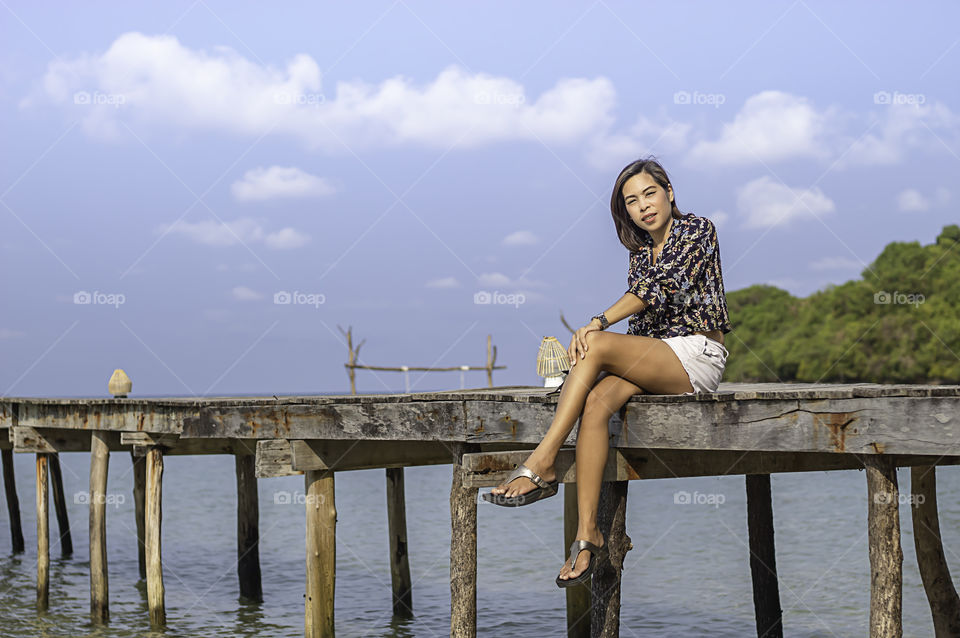 Women on the wooden bridge pier boat in the sea and the bright sky at Koh Kood, Trat in Thailand.