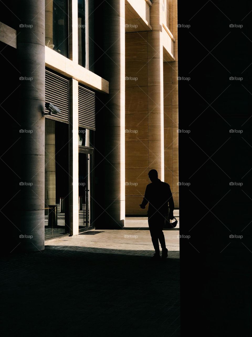 Unrecognisable male going near modern building in sunny day