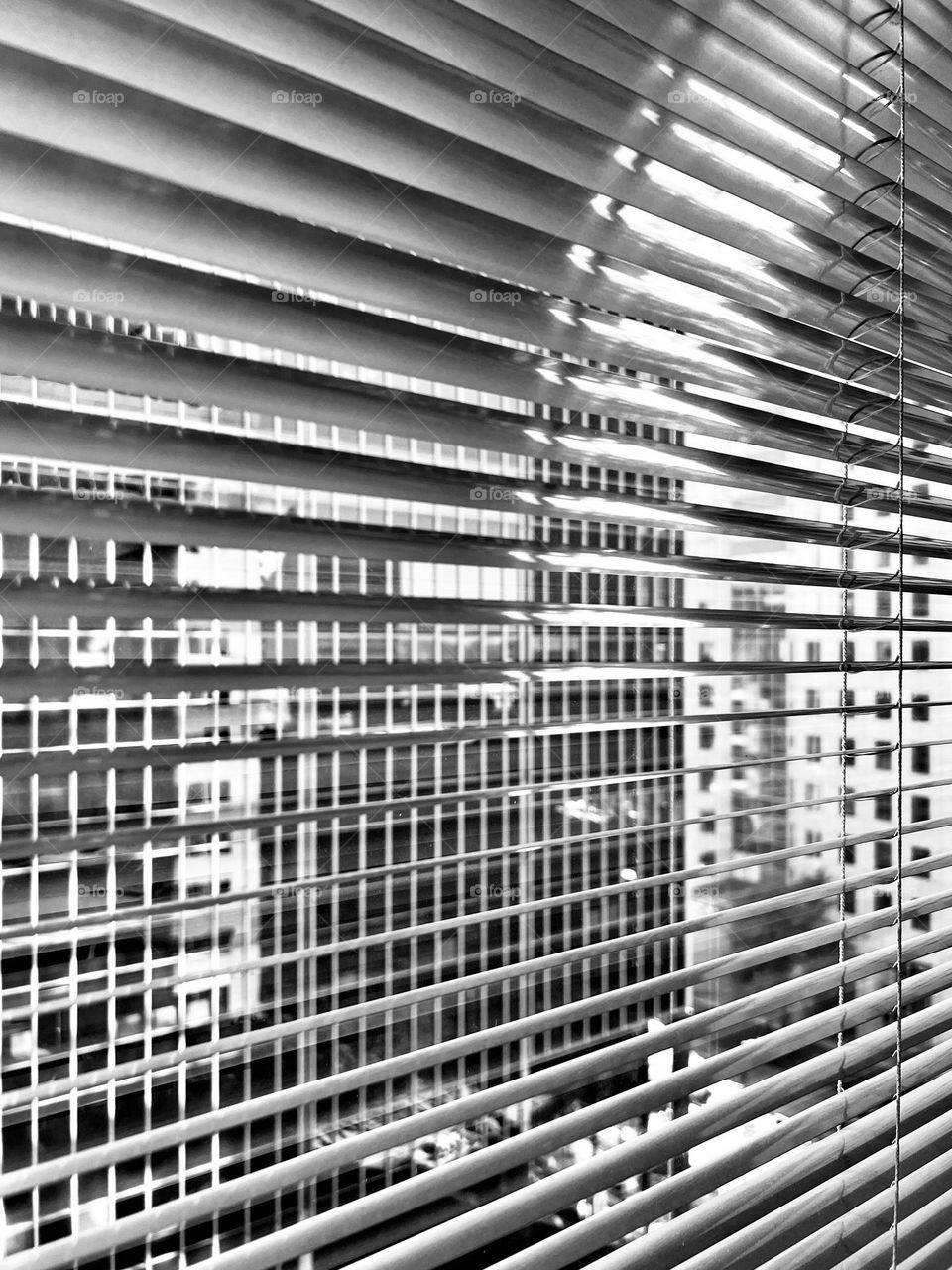 Black and white cityscape as viewed from behind window blinds