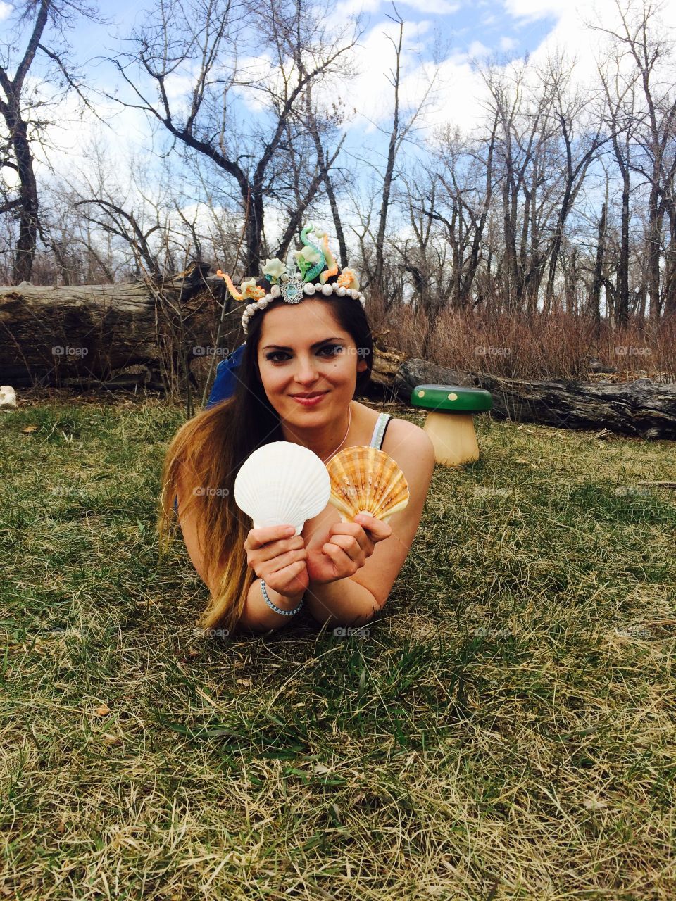 Woman lying on grass and showing seashells