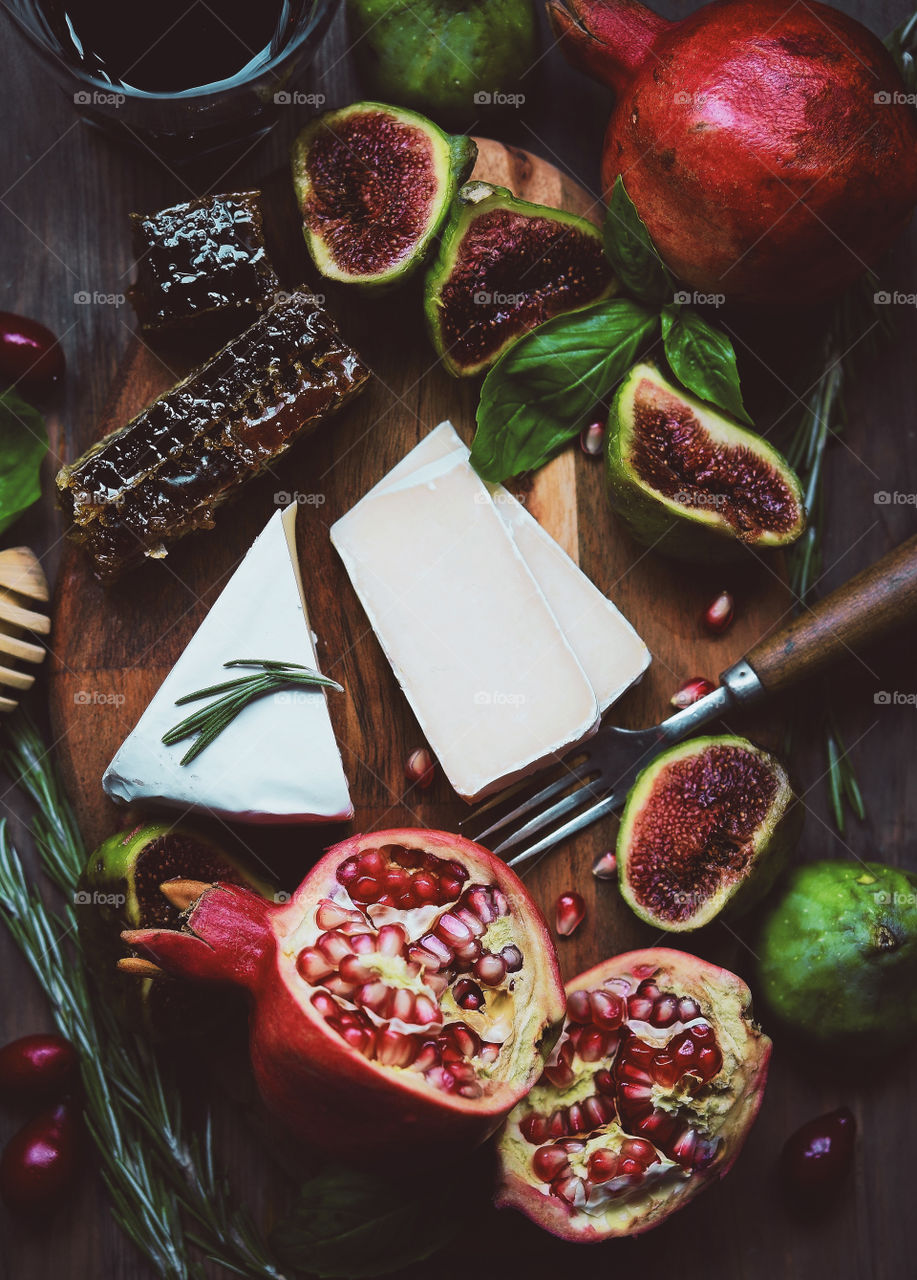 Wooden board with cheese, honey and fruit, top view