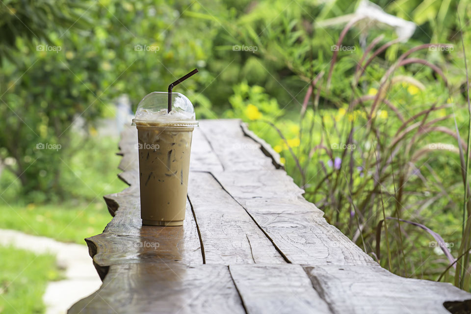 Iced coffee in glass on the table Background  Pennisetum pedicellatum and tree.