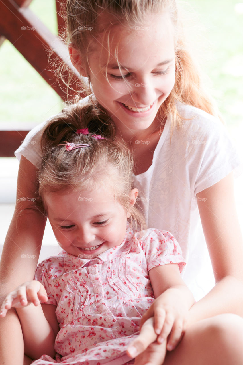 Young girl and her little sister spending time together on tickling and laughing