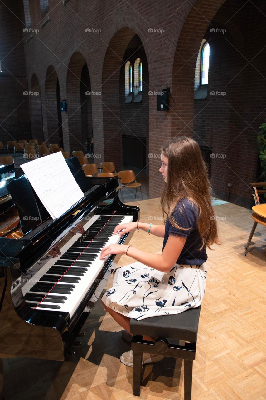 teenage girl playing the piano in the concert hall, hobby, playing music on the instrument

