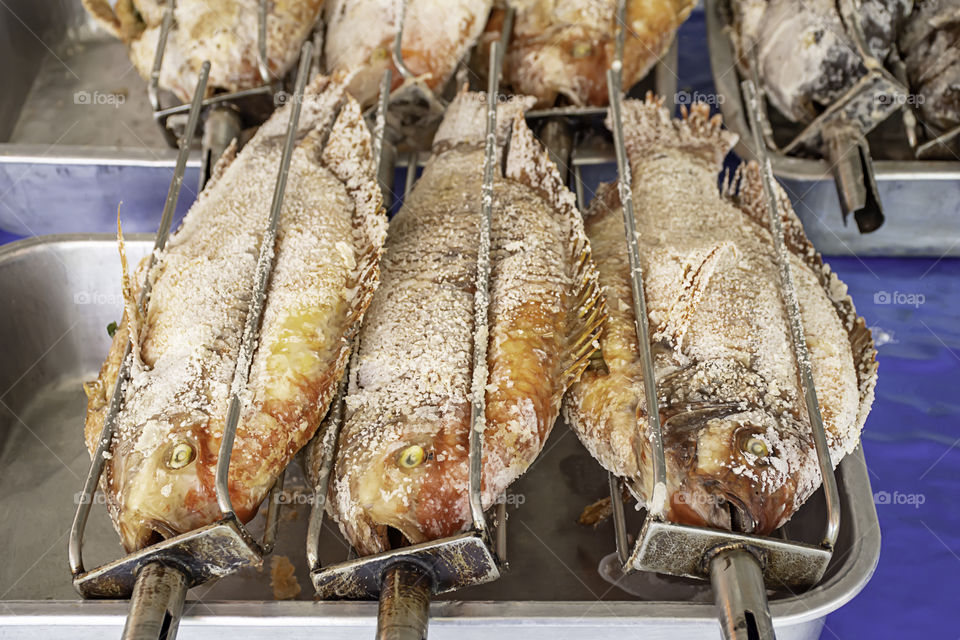 Ruby fish with salt in the grill on the tray.