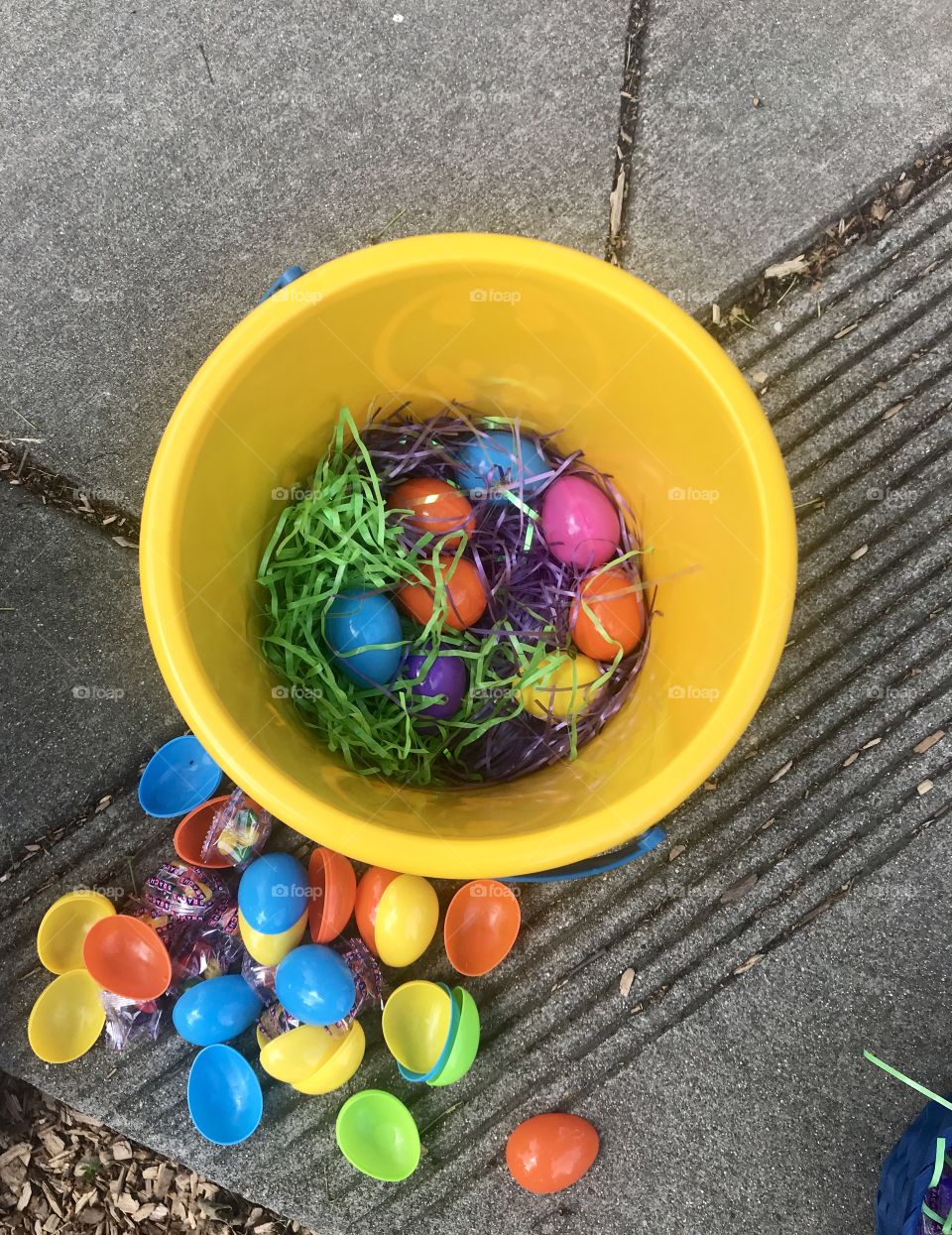 A bright yellow Easter basket filled with green grass and colorful eggs opened to discover the candy and prizes inside each egg.