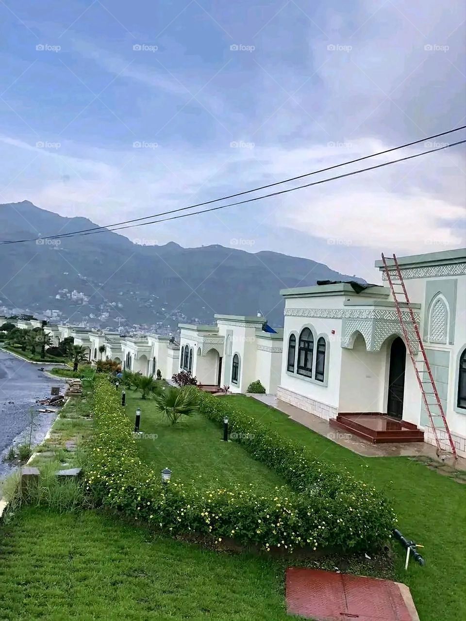 The image embodies a natural natural plate of the mountains of nature, where green agricultural stands are graded on the slopes as if they were lines of a poem, which fog harmoniously wrapped, and clouds hugged them in the mountain knife and the whis