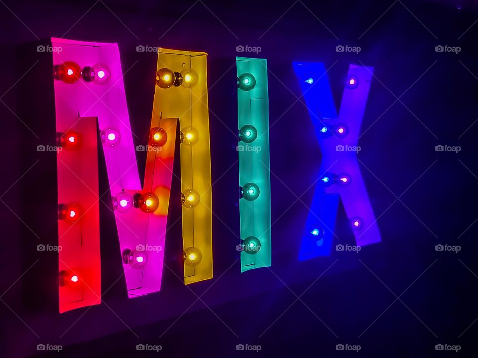 Rainbow colored neon style sign spelling the word MIX at night, with the colors of Pride 