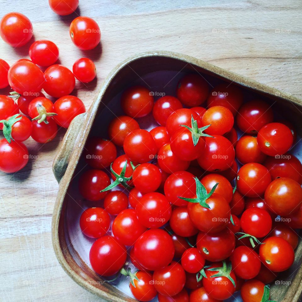 Small red cherry tomatoes harvested from a small city garden and photographed in a bright kitchen window.  Technically a fruit but treated as a vegetable.