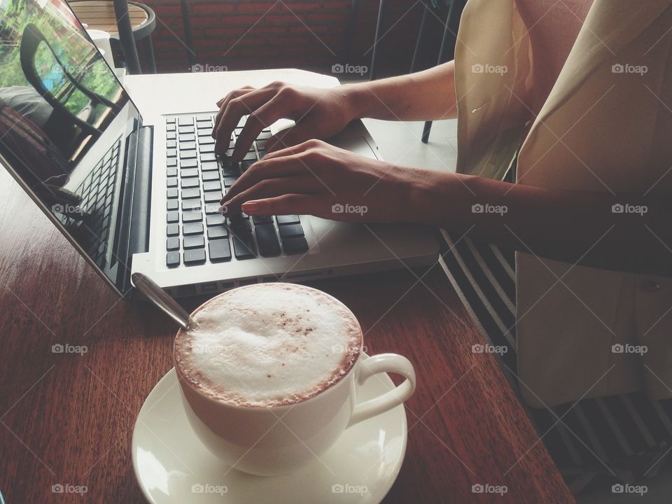 Typing work on a laptop with a cup of coffee