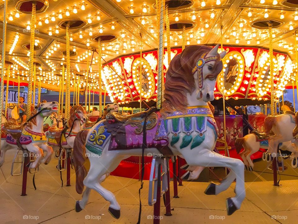 Horses under bright lights. Carousel 