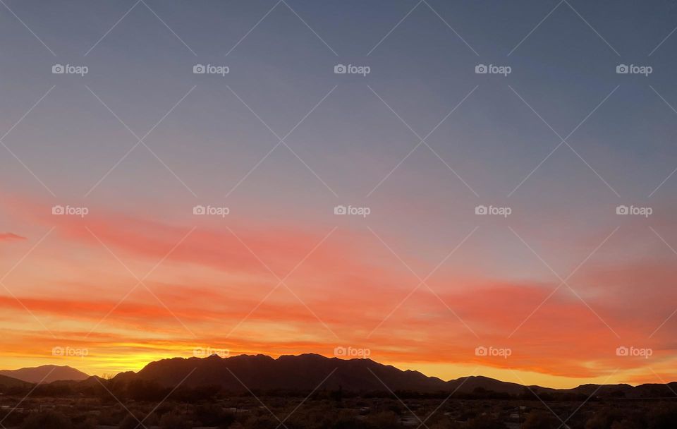 A colorful sunset with clouds and mountains. 