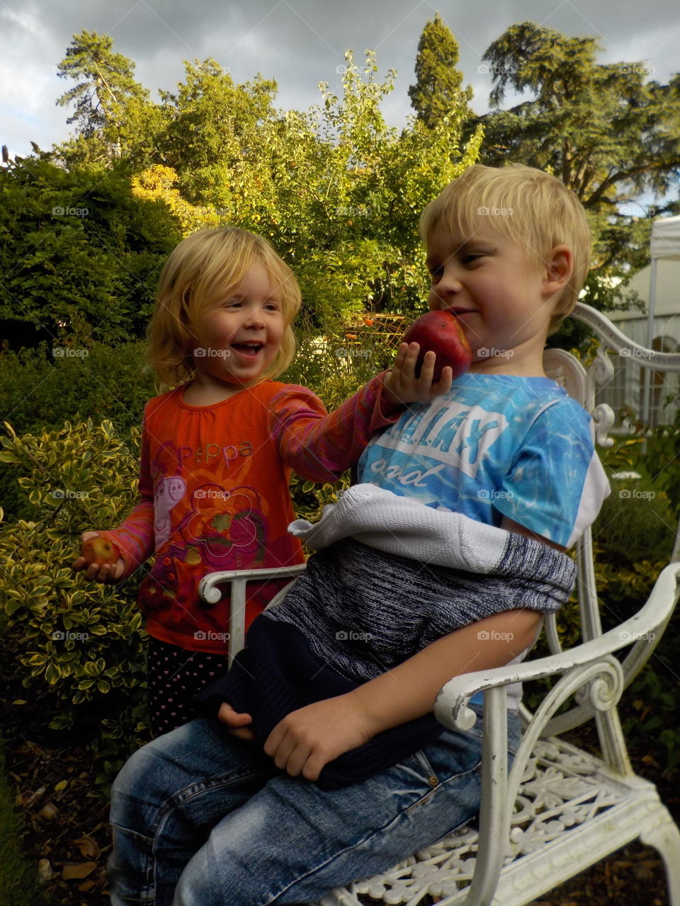 Girl feeding apple to her brother