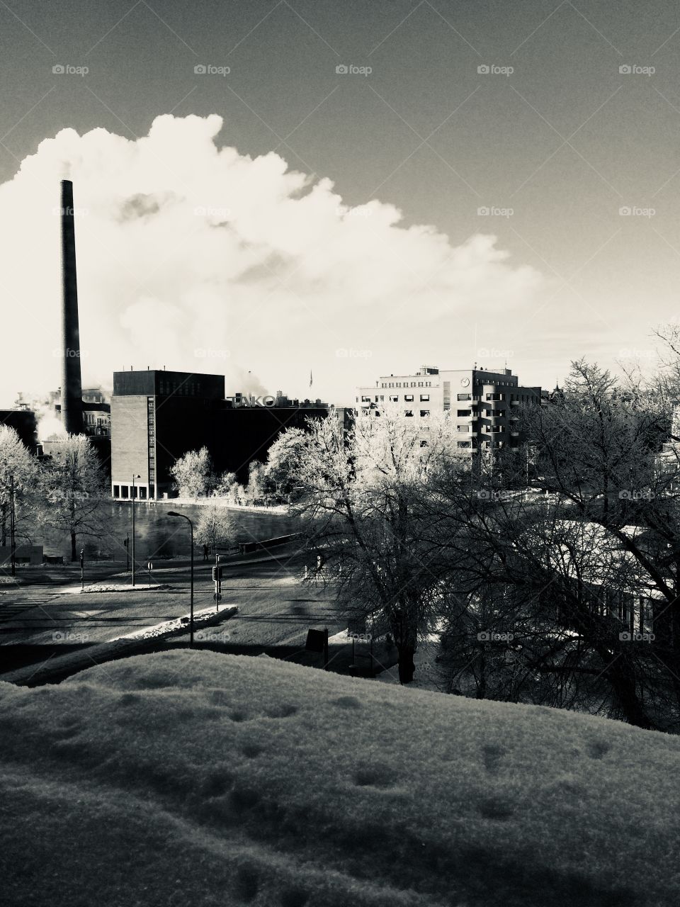 A view from the window to a frosty city with a factory and chimney on a winters day / Black and White 