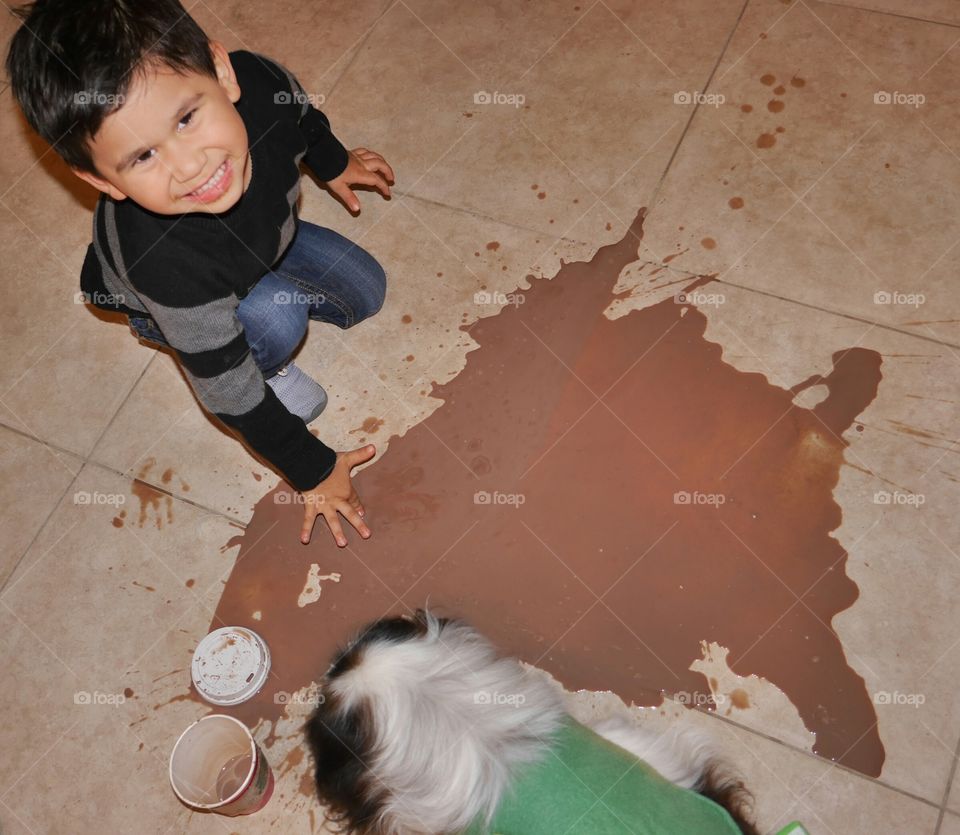 Elevated view of a boy and dog near spilled chocolate shake on floor