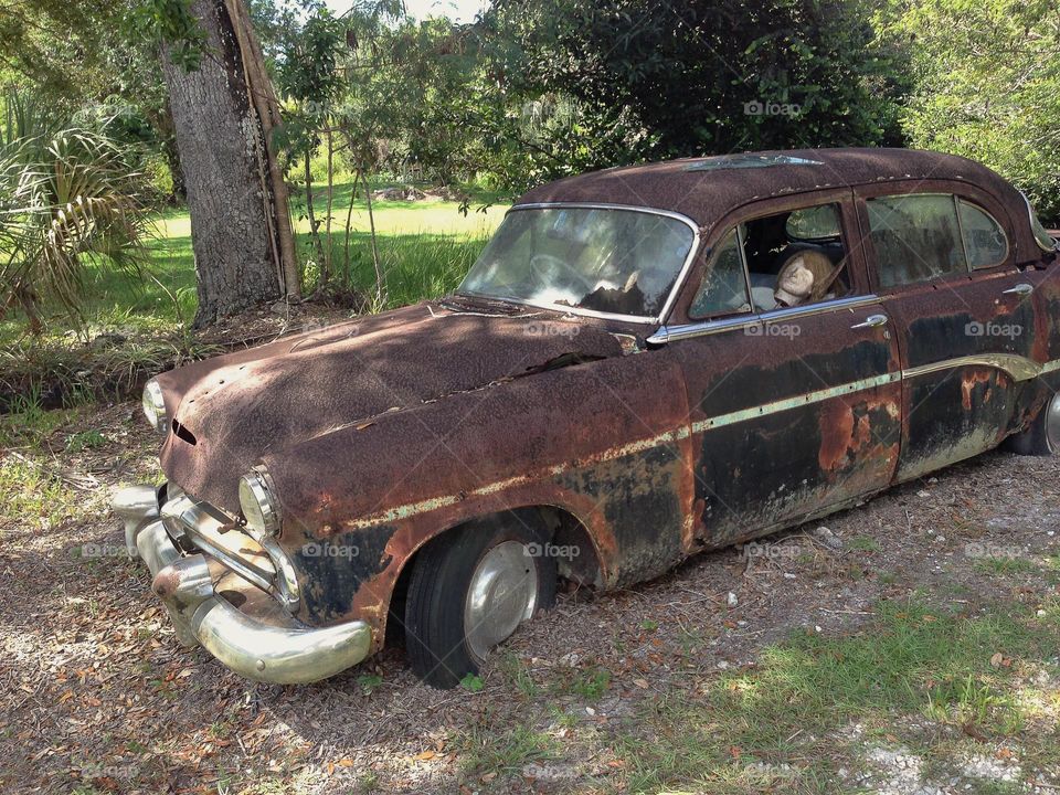 Vintage rusted car with mannequin.