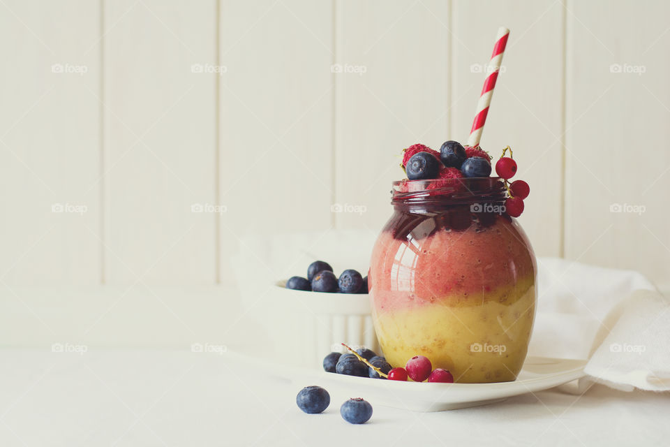 Colorful smoothie with banana, strawberry, raspberry and blueberry in jar