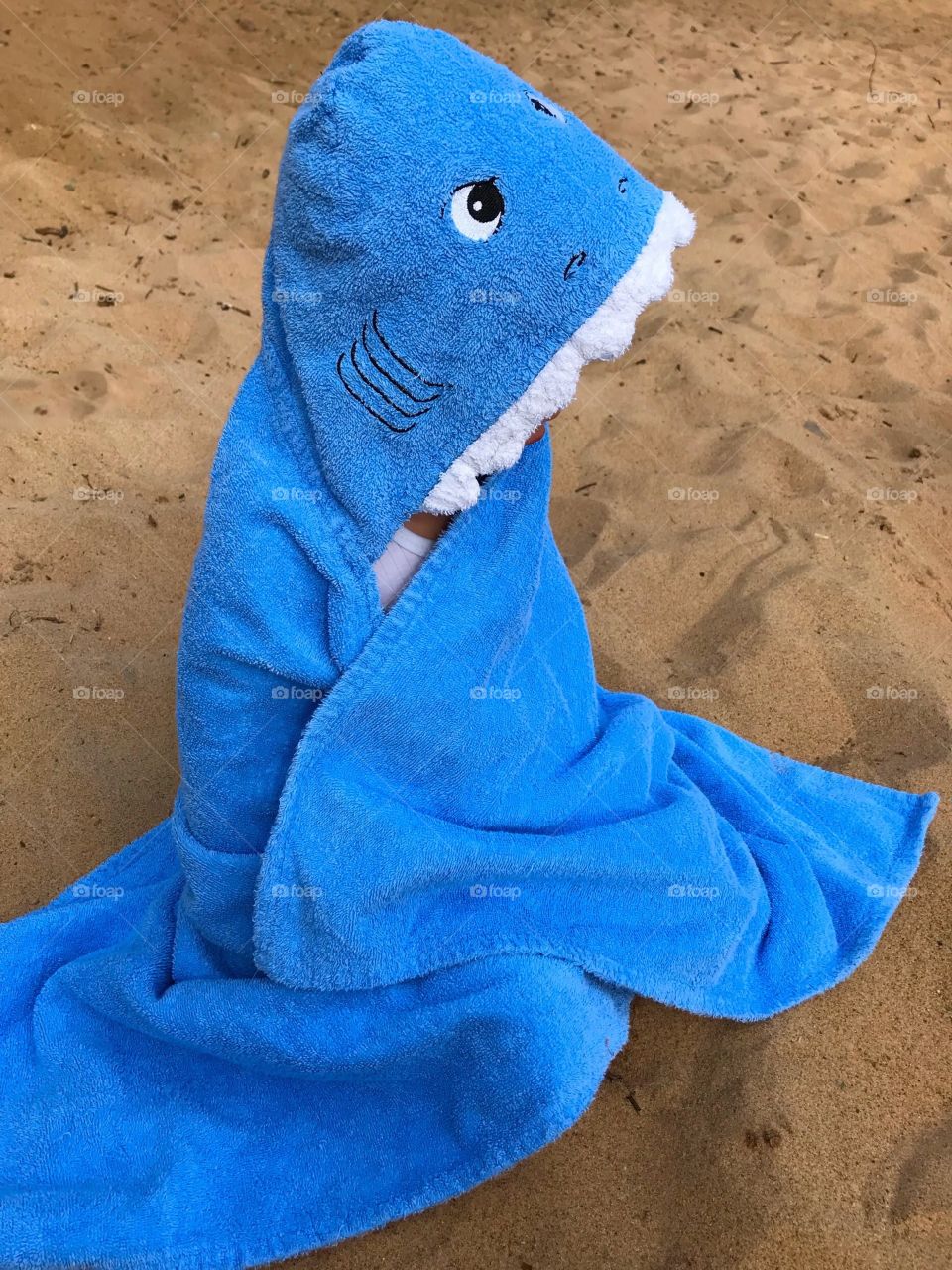 Child wrapped up in a baby shark towel at the beach