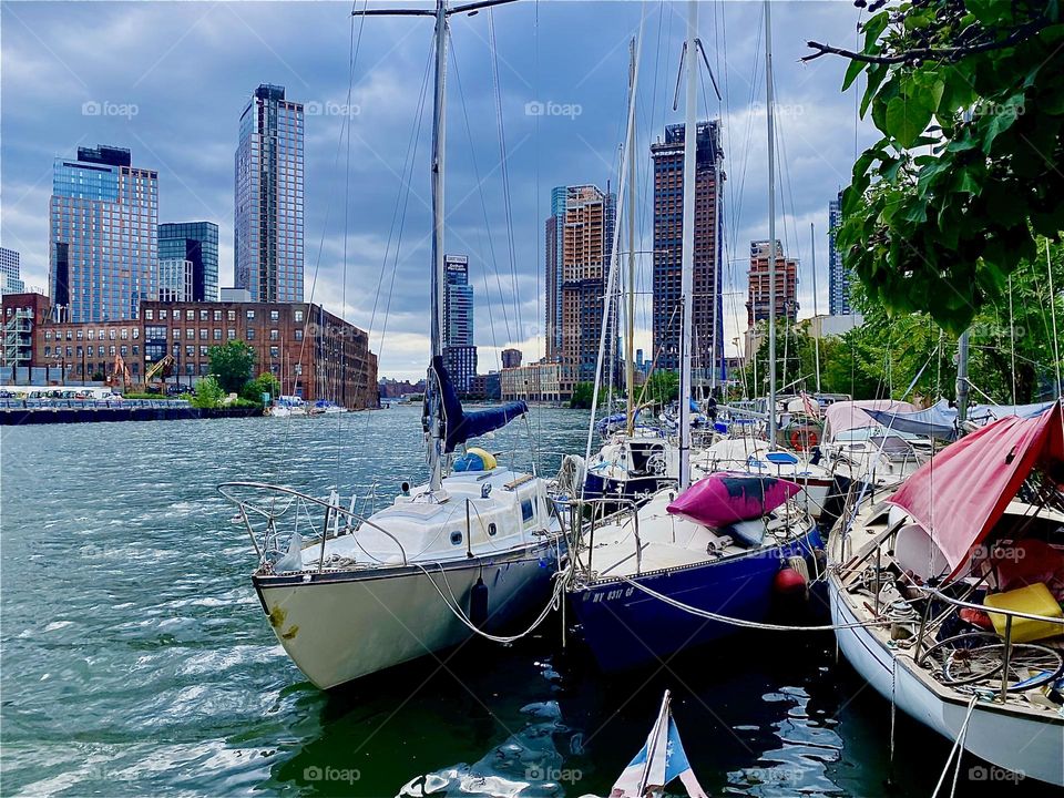 The boats at „Newtown Creek“ by the „Pulaski Bridge“ in LIC, Queens lay peacefully in the water of the „E River“ that sparkles and shimmers in the light of the afternoon sun that is getting ready to set behind the horizon. 2023. Hypnotic Productions