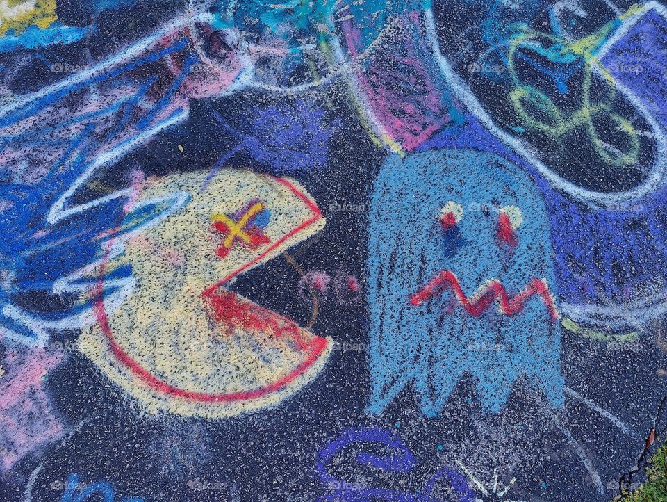 Street art graffiti yellow Pacman chasing scared blue ghost