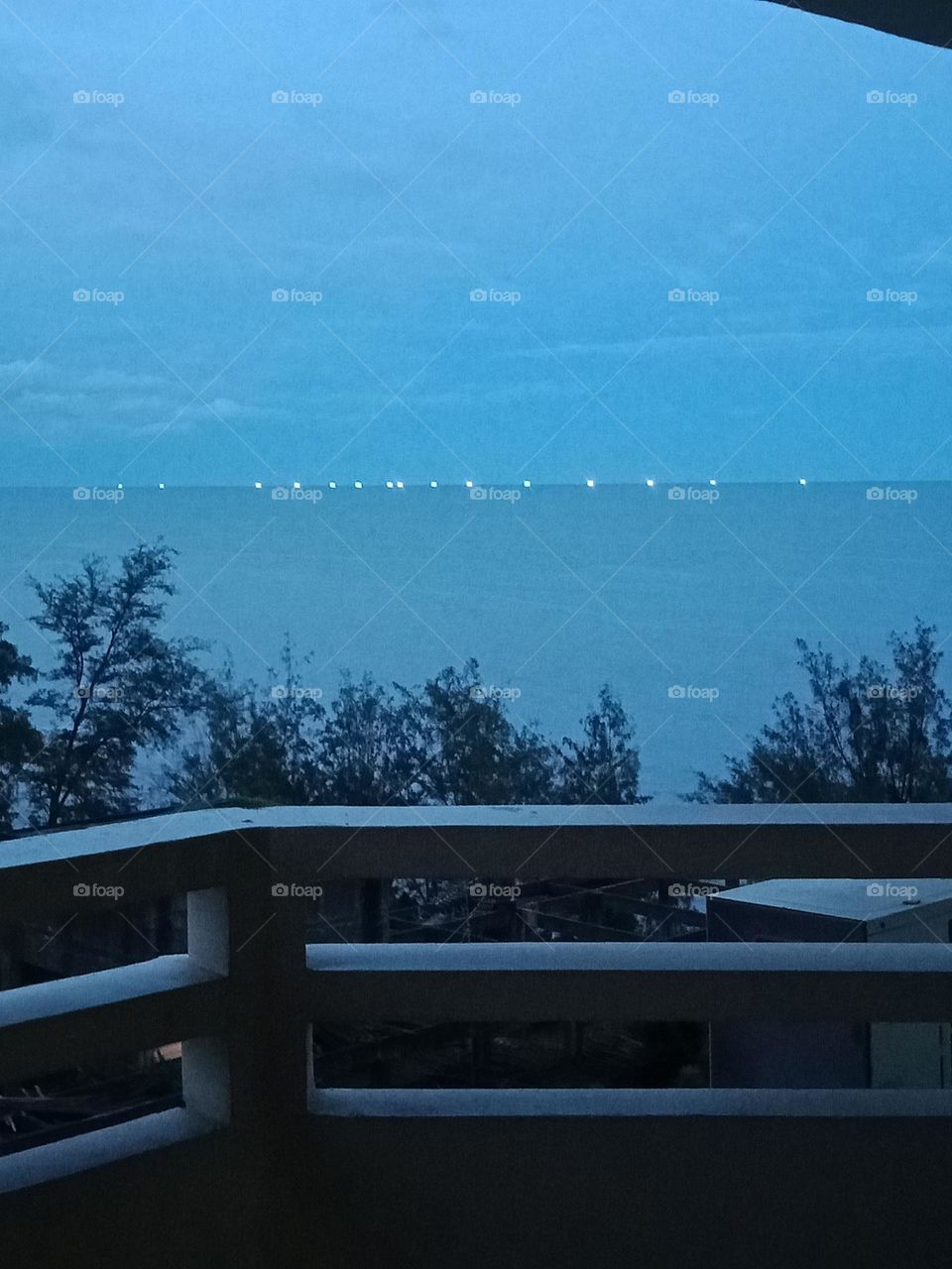 Twilight sea with fishing boats' lights on at horizon