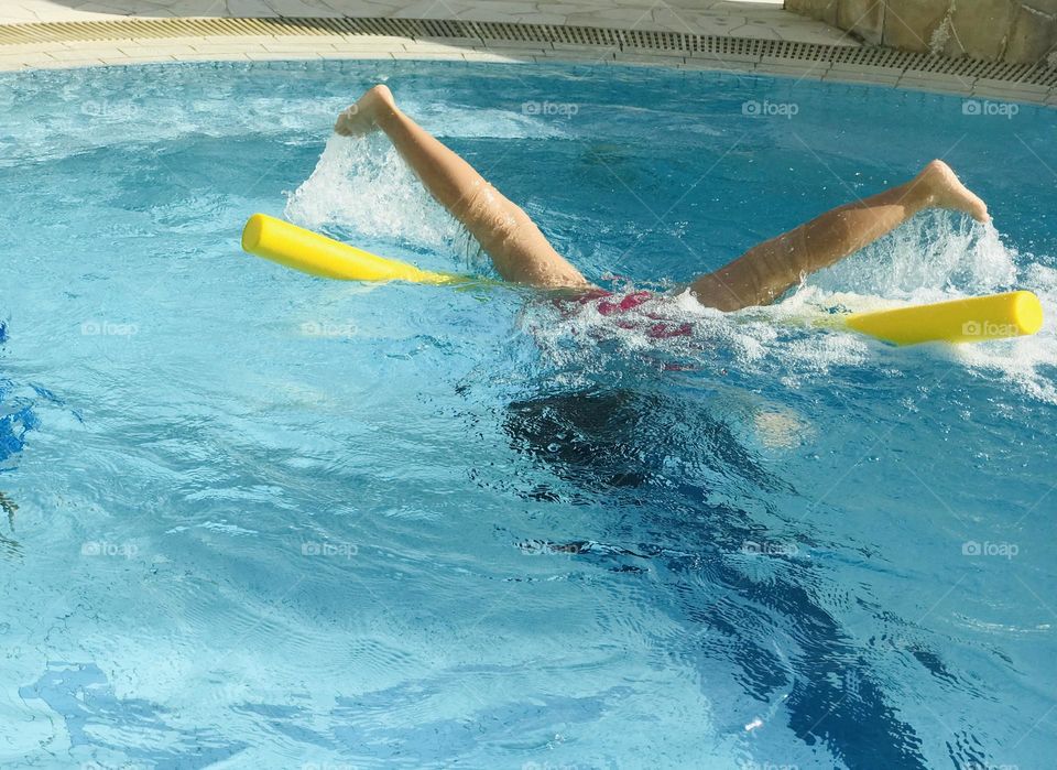 A girl swimming at pool and she put her half body in the water and legs above the water.