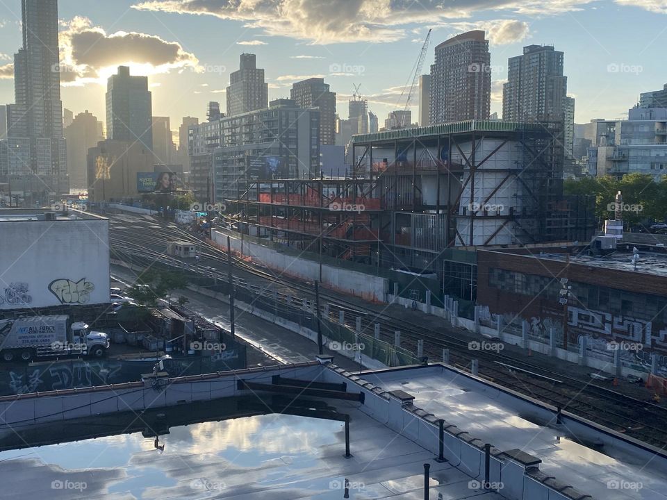 This is an overview of the train tracks in “Long Island City”, Queens seen while descending the staircase of the “Pulaski Bridge” at “Newtown Creek” at dusk. 2023. Hypnotic Productions