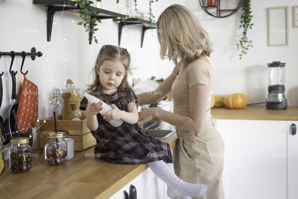 Woman cooking at home with her toddler daughter 