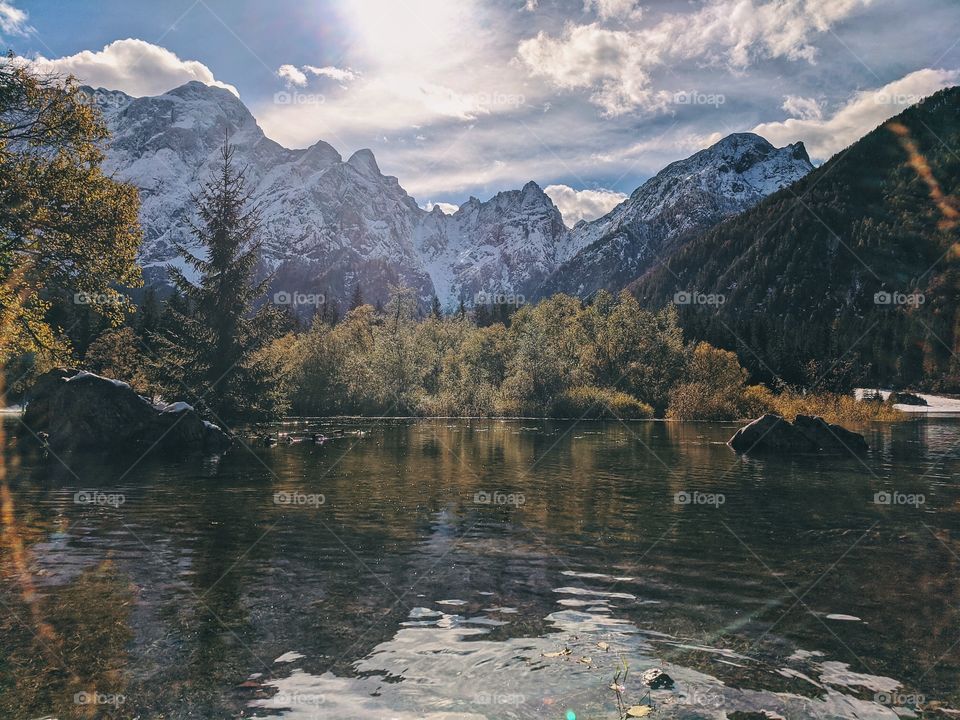 View of the autumn snow-capped mountain peaks against the backdrop of a transparent Italian lake.