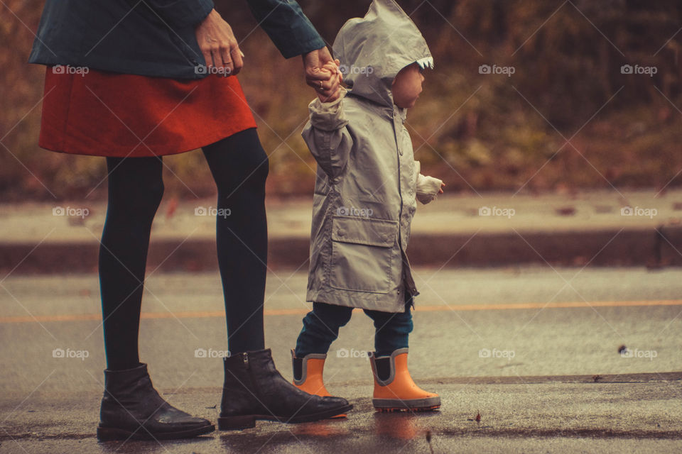 Mother and toddler are walking in the rain