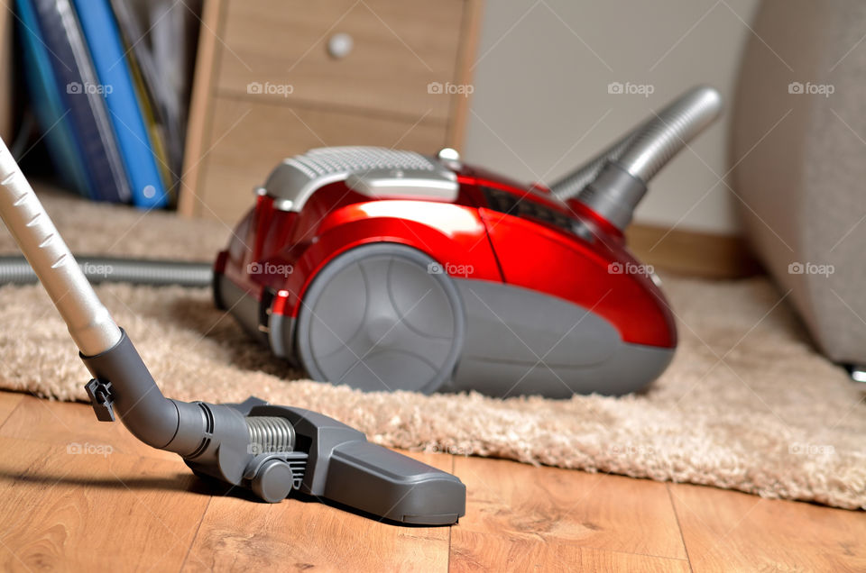 Red modern vacuum cleaner on shaggy carpet