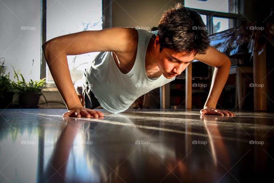 Young man is doing pushups on the floor in his apartment