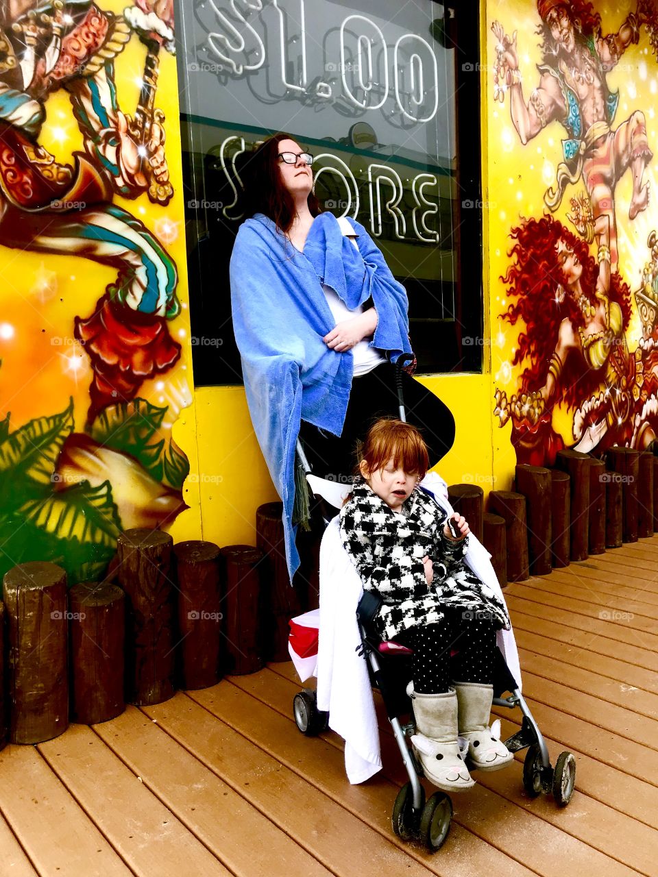 Mom and daughter stopping to take in the sights and sounds of the ocean city boardwalk. Women with stroller in towel up against yellow wall