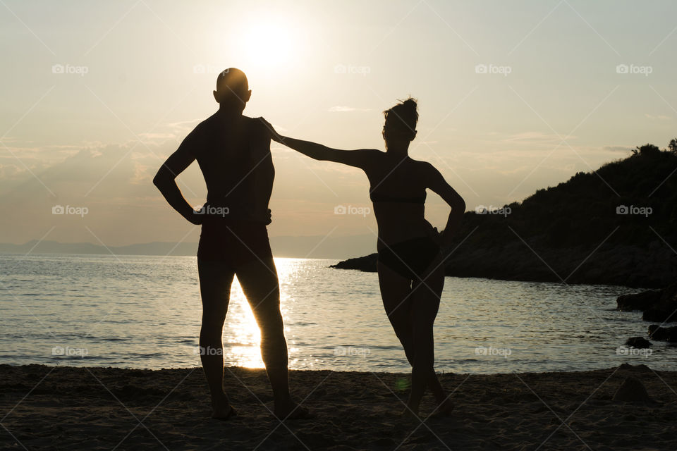 couple silhouettes at sunset. couple silhouettes on beach at sunset