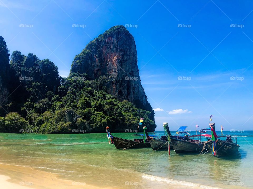 Long tail boats at the shoreline on Railay Beach In Krabi Thailand 