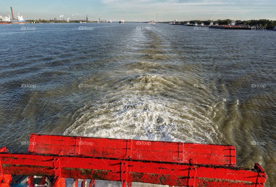 Bright red paddles of the steamboat Natchez. Waves trailing behind on the Mississippi River. New Orleans, Louisiana, USA.