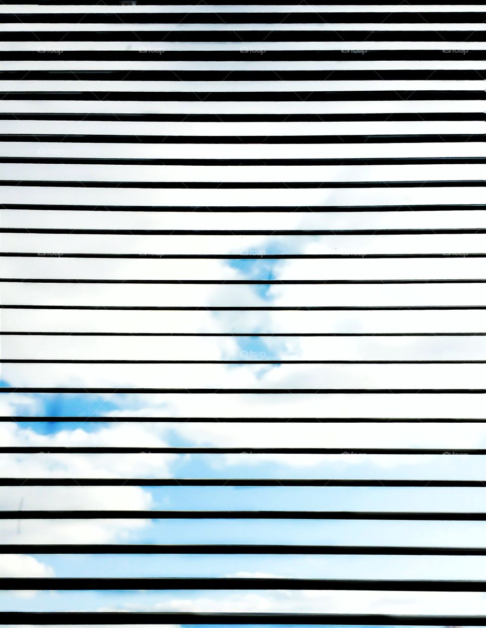 looking at blue sky and clouds through window blinds
