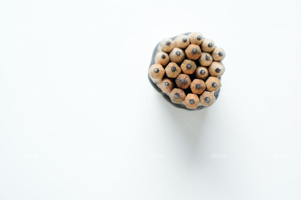 Bunch of simple wooden pencils frome above standing on white background