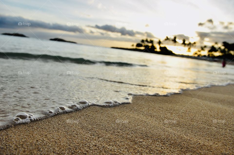 Gorgeous golden bright yellow sun is setting off in the distant horizon with sandy beach in forefront! 