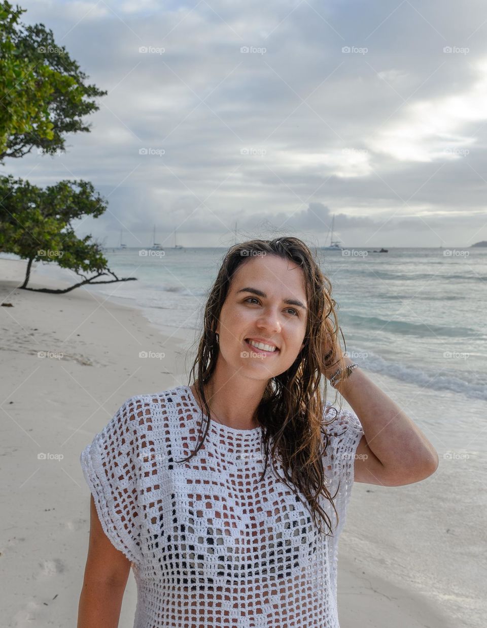 Portrait of happy young woman with wet hair wearing beach clothes on a tropical sandy beach