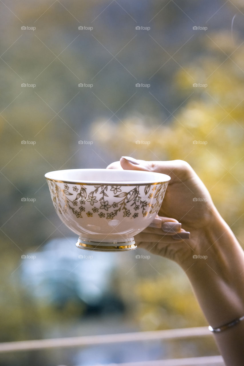 A girl holding a cup.of tea in her hand