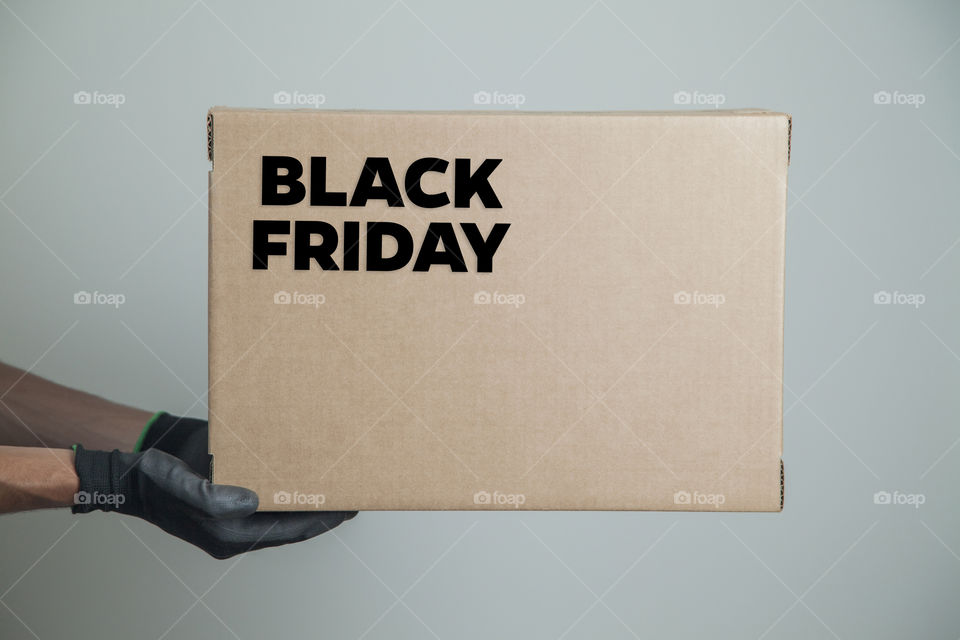Cardboard box with black friday order written on the box placed on the floor in an empty room with a neutral background. delivery concept. economy concept. black friday concept. shopping concept.
