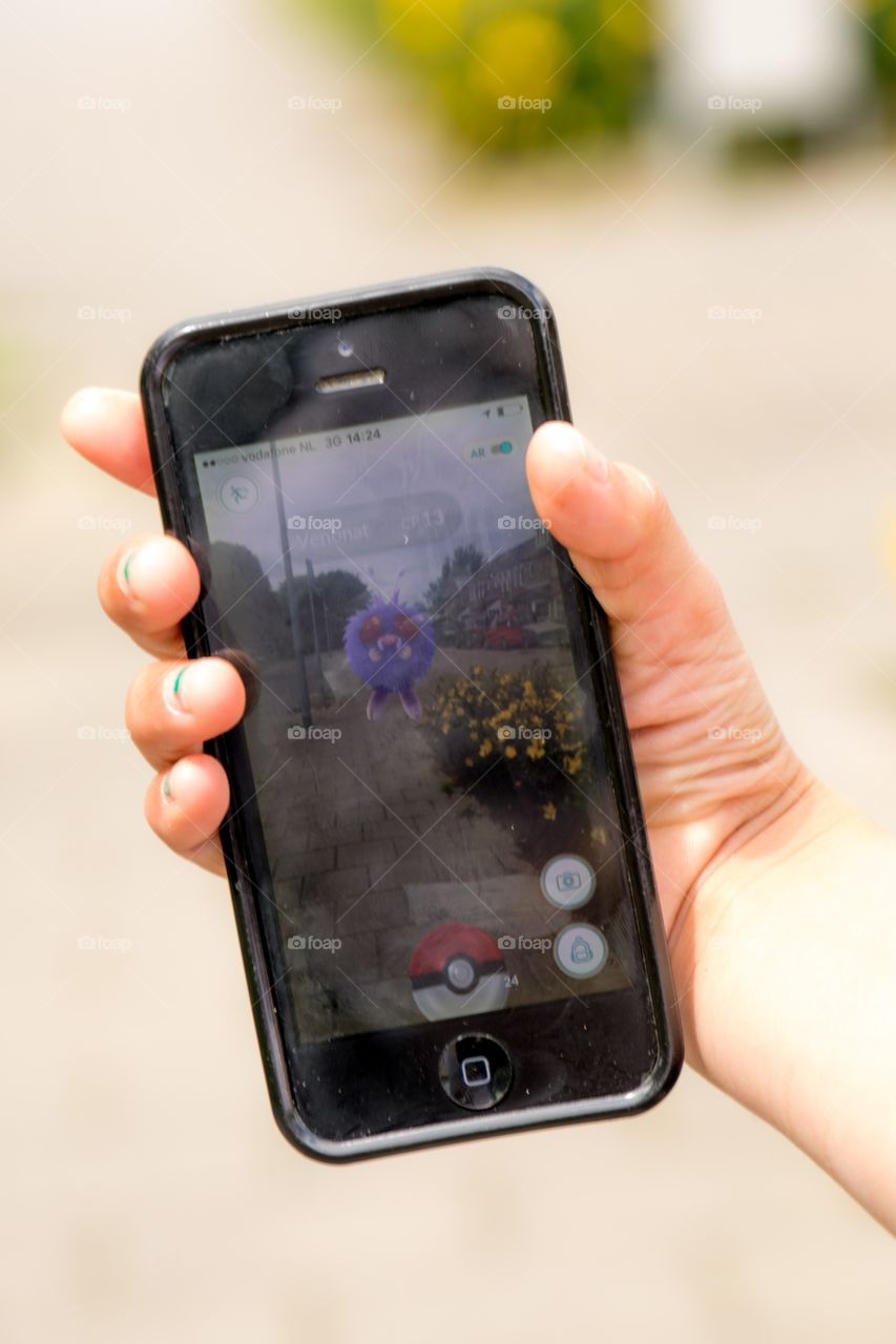 A hand holding a phone while playing Pokémon-go