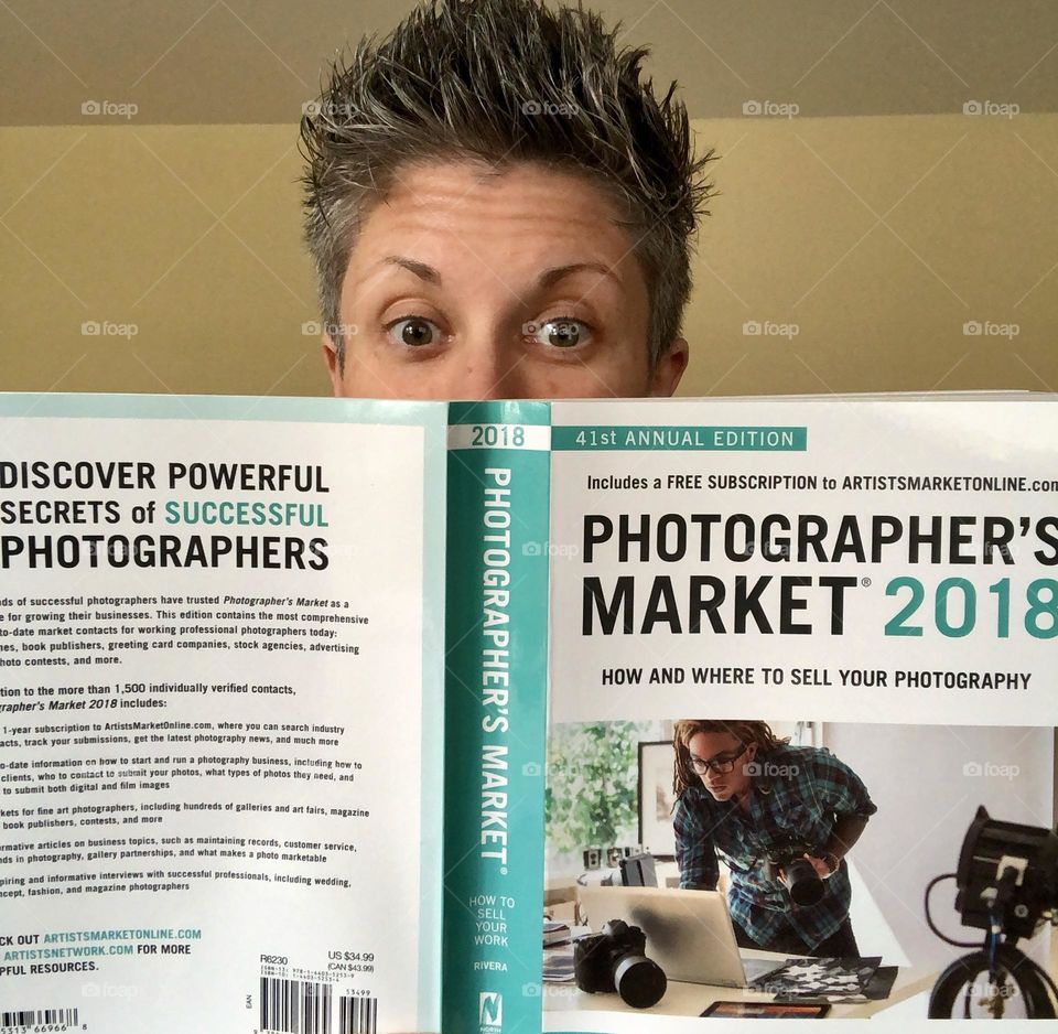 Woman reading photography book, photographer’s market book from 2018, being silly with a book, woman acts funny