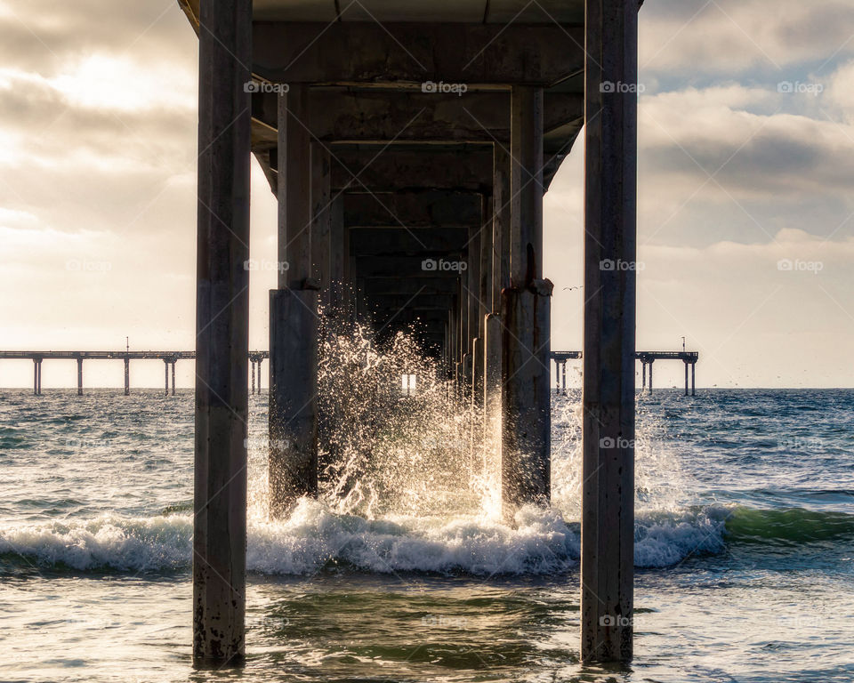 frozen wave bathed in golden light at sunset under the pier