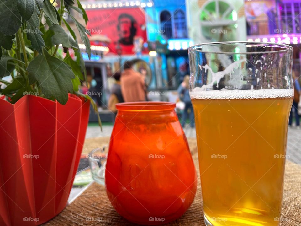 A glass of beer on a table with flowers and candle in the city