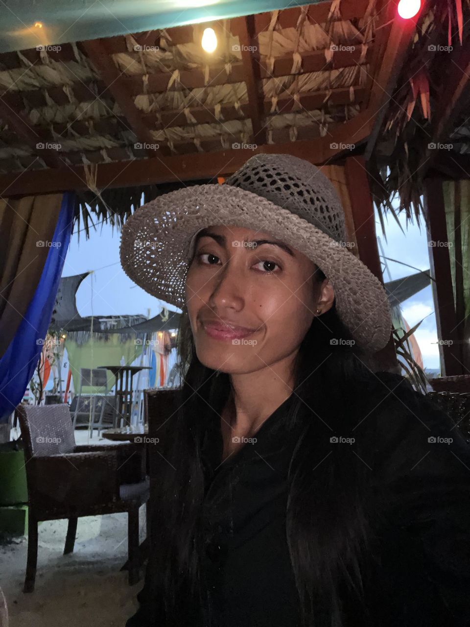 Portrait - selfie of a woman wearing black shirt and gray hat sitting inside the restaurant.